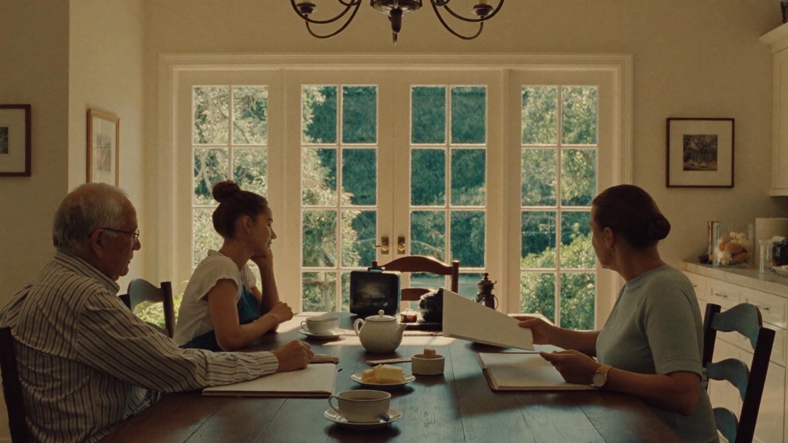 An older man, his adult daughter and a care lead reviewing a plan at the family kitchen table.