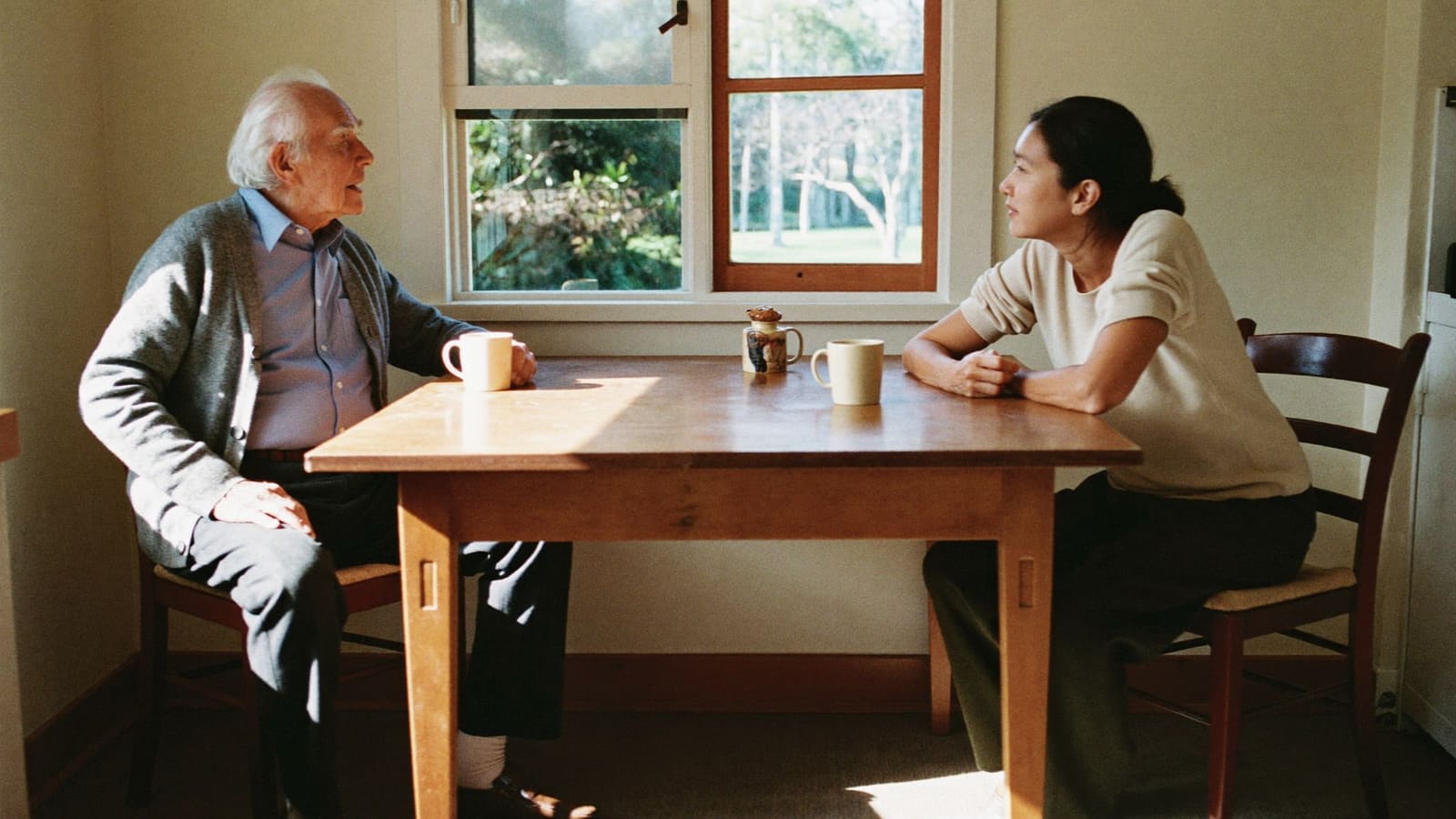 An older man and a support worker talking over tea at a kitchen table on a first visit.