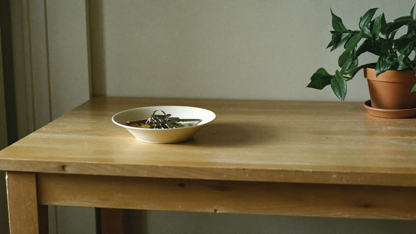 A bunch of house keys resting in a shallow cream bowl on a hall table, where they are always left.