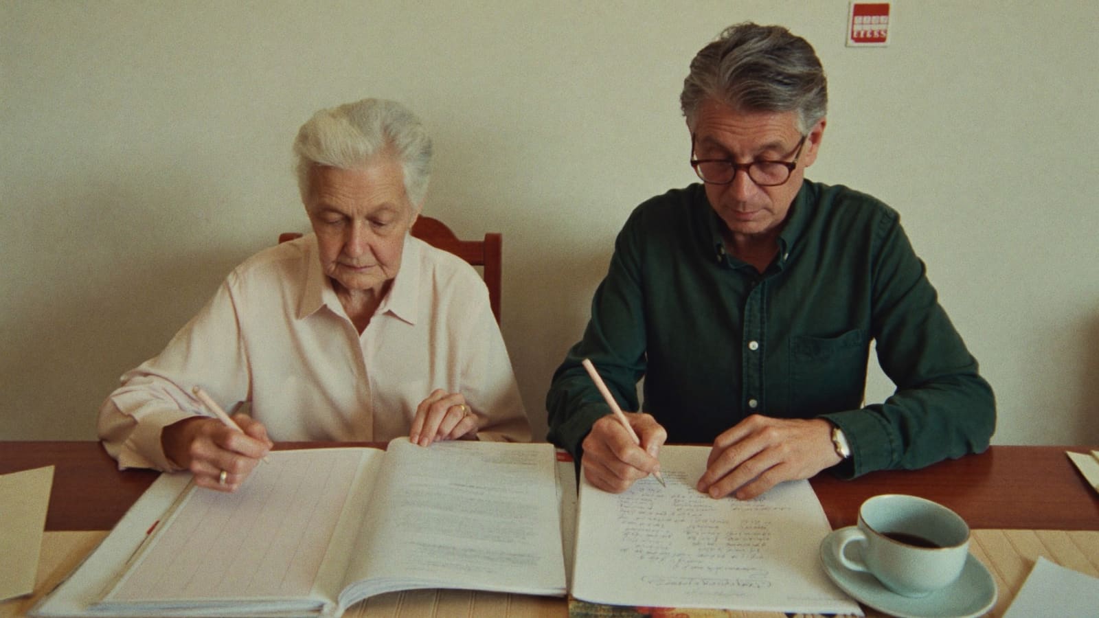An older woman and her adult son working through a folder of documents and a handwritten checklist together.